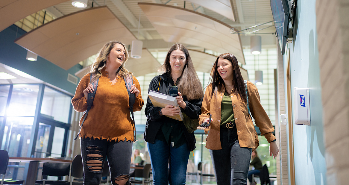 Three young women walking through a large foyer
