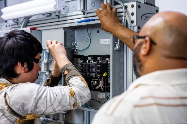 Male Electrical Student using equipment with instructor