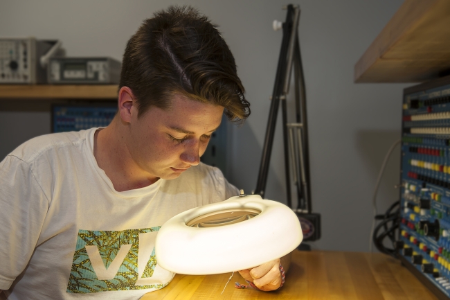 Male student looking at electronic parts